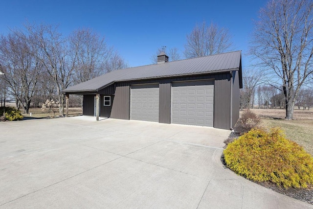 exterior space featuring a garage, metal roof, an outdoor structure, and a chimney