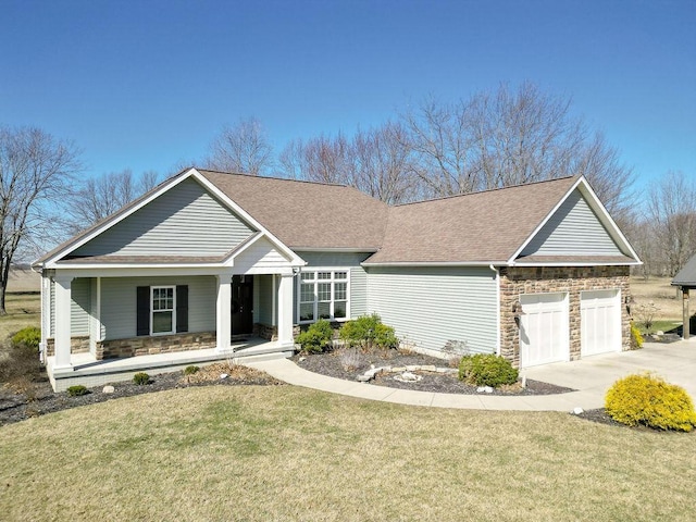 view of front of property with a front yard, an attached garage, covered porch, and stone siding