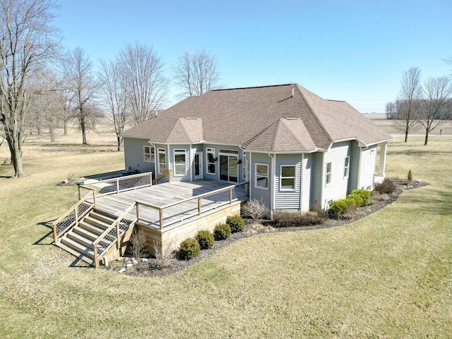 rear view of house featuring a deck, a yard, and roof with shingles