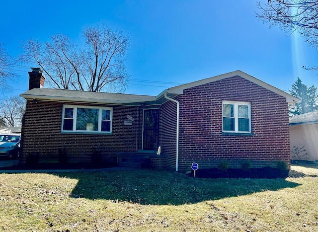 view of front facade featuring a front yard, brick siding, and a chimney