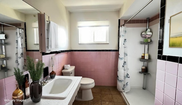 bathroom featuring a shower with curtain, a sink, tile patterned flooring, tile walls, and toilet