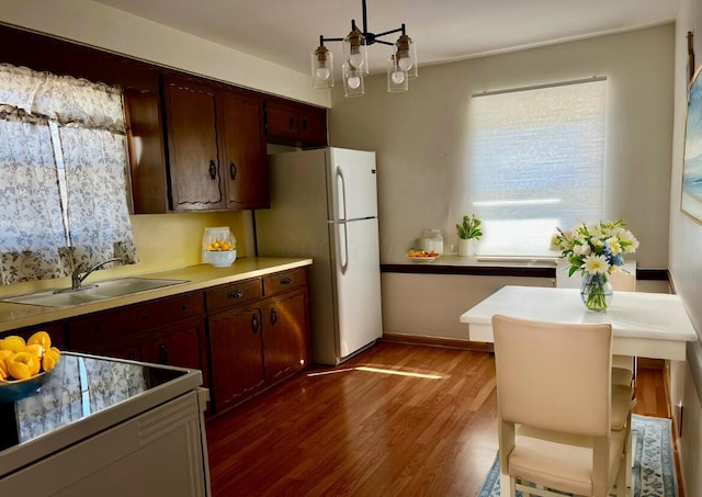 kitchen featuring dark wood-style floors, freestanding refrigerator, a sink, stove, and tile counters