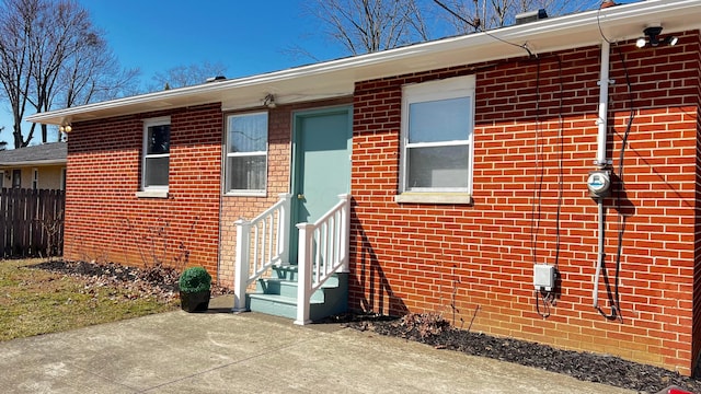 exterior space with entry steps, fence, and brick siding