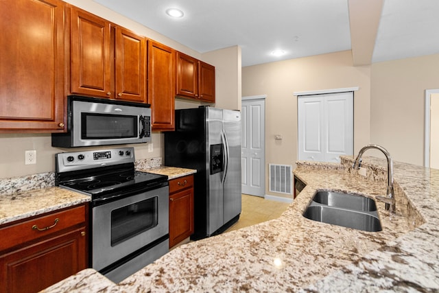 kitchen featuring visible vents, appliances with stainless steel finishes, light stone countertops, and a sink