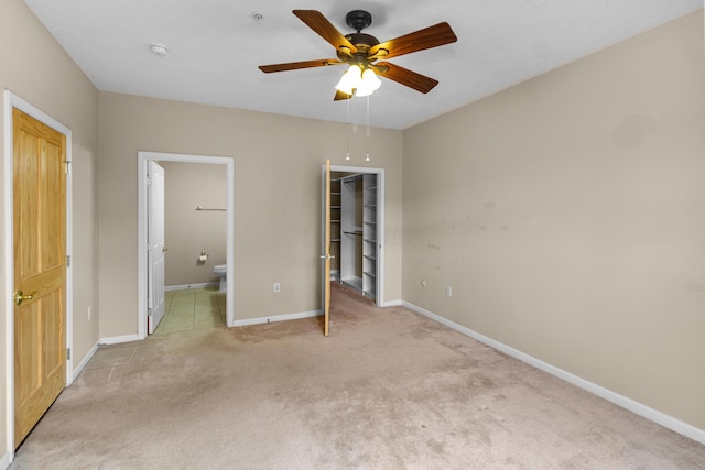 unfurnished bedroom with baseboards, ensuite bath, a spacious closet, a closet, and light colored carpet