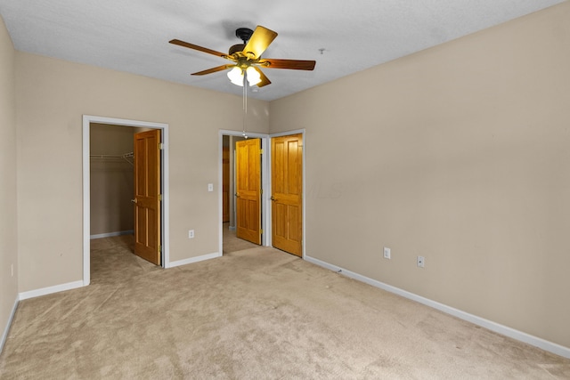 unfurnished bedroom featuring a spacious closet, baseboards, a closet, and carpet