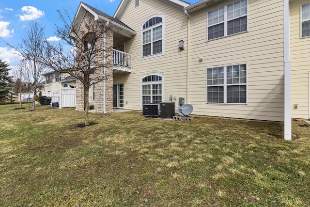 rear view of house featuring a balcony, cooling unit, and a yard