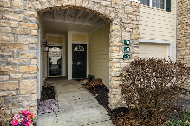 view of exterior entry with stone siding and a garage