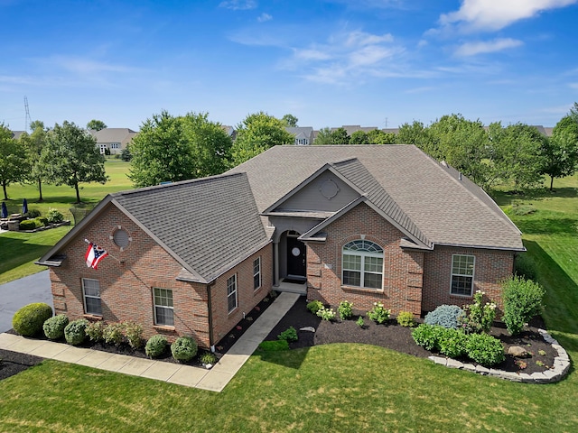 single story home featuring brick siding, roof with shingles, and a front lawn