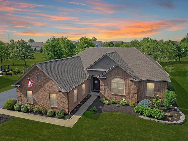 ranch-style house featuring brick siding, a front yard, and a shingled roof