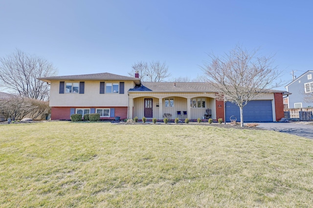 split level home featuring aphalt driveway, covered porch, an attached garage, a front yard, and a chimney