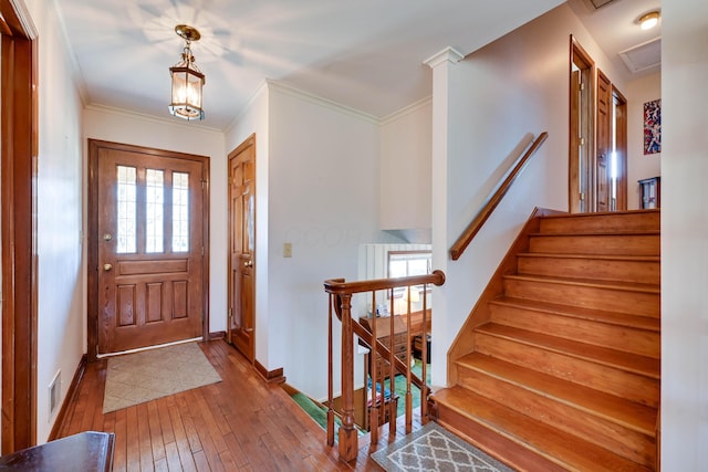 entrance foyer featuring visible vents, ornamental molding, baseboards, and wood-type flooring