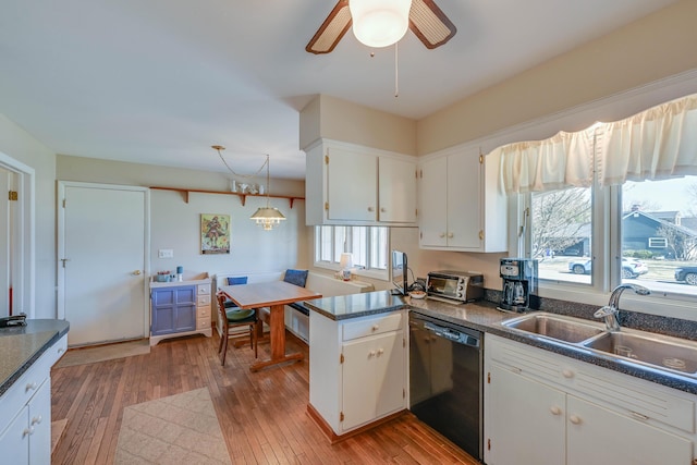 kitchen with a sink, dark countertops, light wood-style floors, white cabinets, and dishwasher