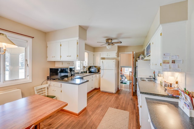 kitchen with light wood finished floors, dark countertops, a healthy amount of sunlight, and freestanding refrigerator