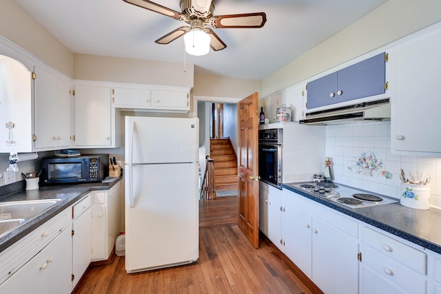 kitchen with ventilation hood, oven, black microwave, freestanding refrigerator, and electric stovetop