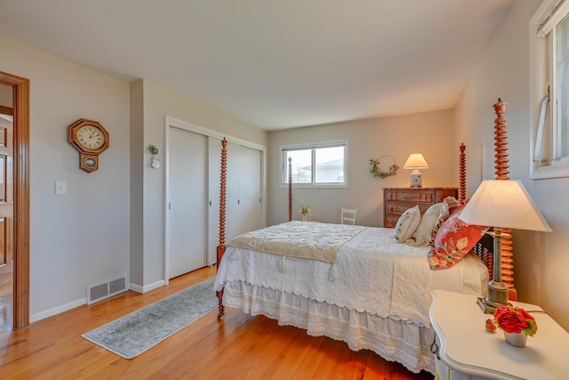 bedroom with a closet, visible vents, baseboards, and wood finished floors