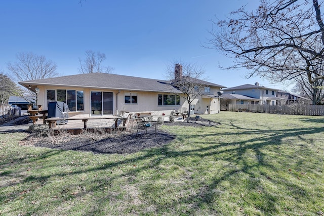 rear view of house with stucco siding, a lawn, a chimney, and fence