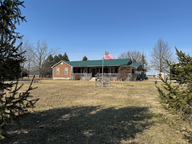 back of property with covered porch, metal roof, and a lawn