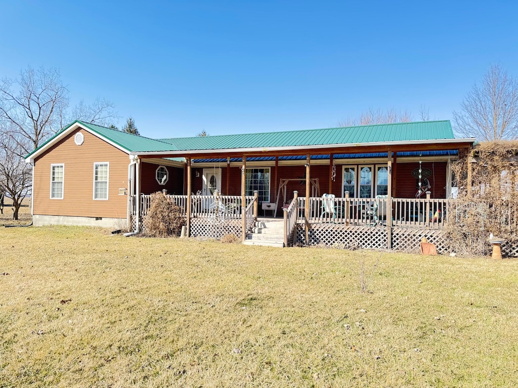 view of front of house with metal roof, covered porch, and a front lawn