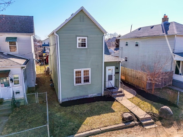 rear view of house with a gate, a yard, entry steps, and fence