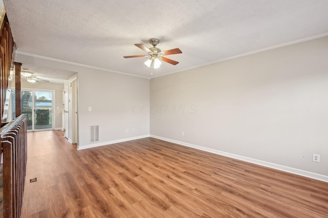 unfurnished room with visible vents, a textured ceiling, crown molding, light wood finished floors, and baseboards