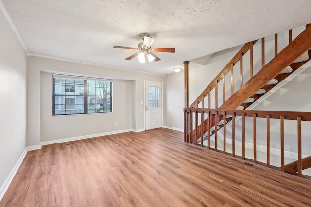 foyer featuring baseboards, a textured ceiling, wood finished floors, and stairs