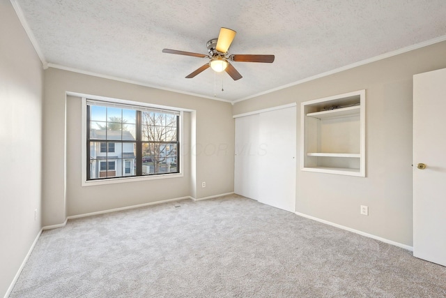 unfurnished bedroom with a ceiling fan, carpet, ornamental molding, a closet, and a textured ceiling