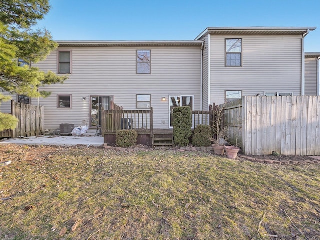 rear view of house with a patio, central AC unit, fence, a wooden deck, and a lawn