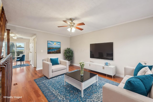 living area with baseboards, light wood-style flooring, a ceiling fan, and crown molding