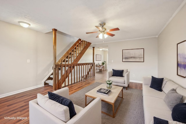 living area with stairway, wood finished floors, baseboards, and ceiling fan