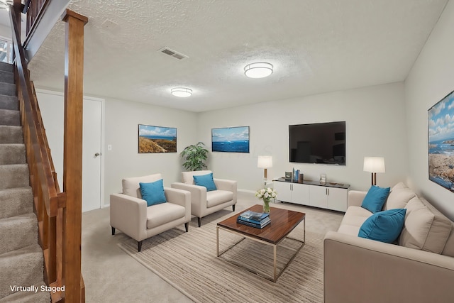 living room with visible vents, light colored carpet, stairway, and a textured ceiling