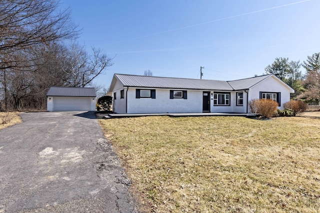 ranch-style home with an outbuilding, a front lawn, a detached garage, and metal roof