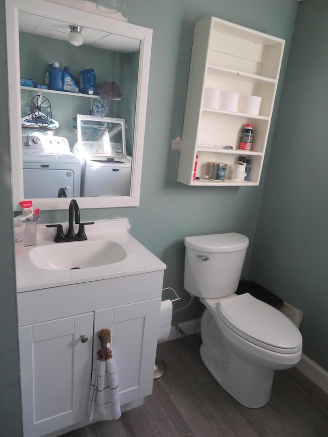 half bath with baseboards, toilet, wood finished floors, independent washer and dryer, and vanity