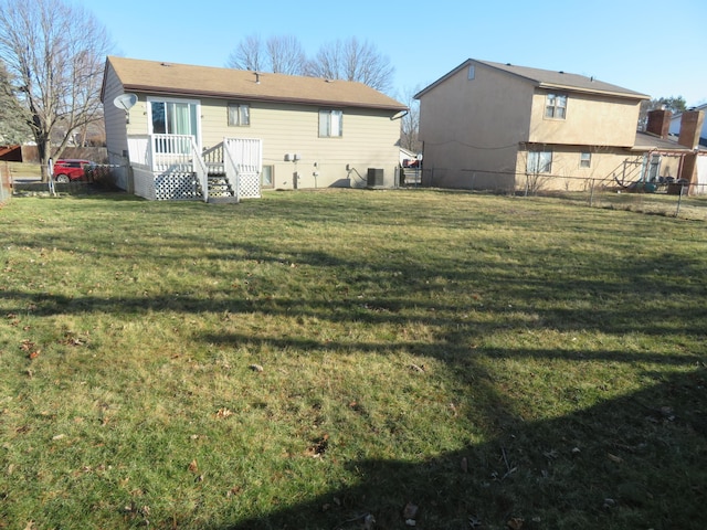 back of property with central air condition unit, a lawn, and fence