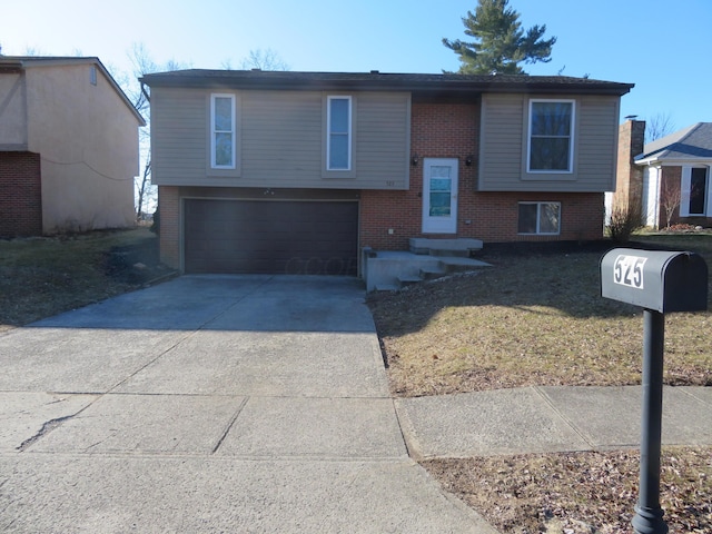 bi-level home featuring brick siding, entry steps, concrete driveway, a front yard, and an attached garage