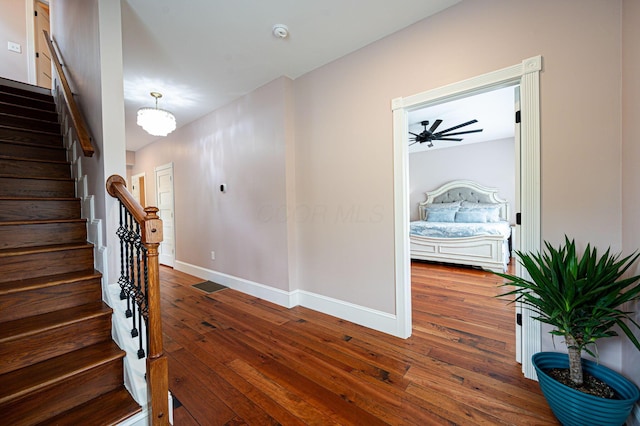 hallway featuring stairway, wood-type flooring, and baseboards