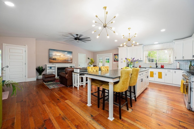 kitchen featuring a breakfast bar, high end stove, white cabinets, light wood-type flooring, and a center island