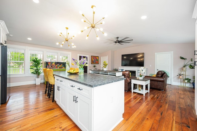 kitchen featuring lofted ceiling, light wood-style flooring, freestanding refrigerator, white cabinetry, and a center island