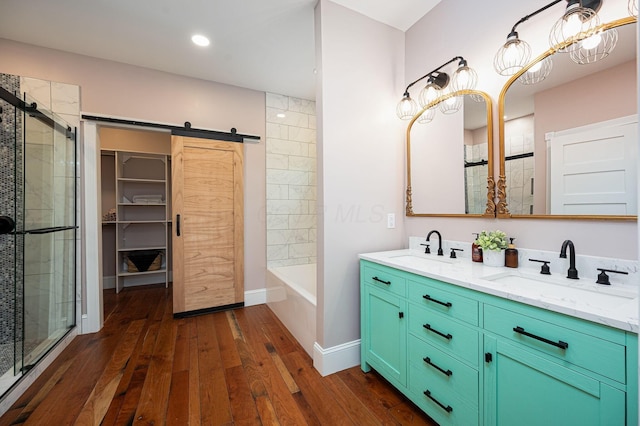 bathroom with a sink, wood-type flooring, double vanity, and a tile shower