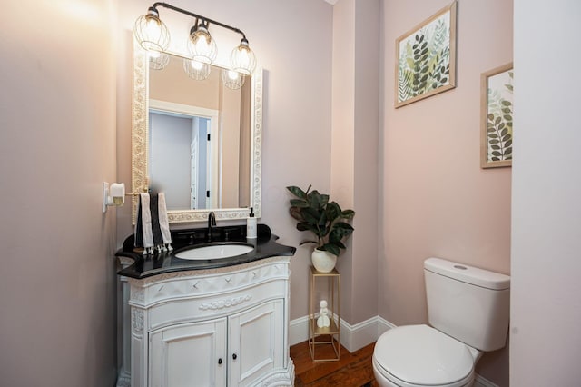 half bath with toilet, vanity, and baseboards