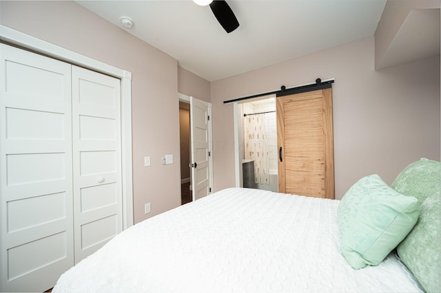 bedroom featuring a closet, ceiling fan, ensuite bath, and a barn door