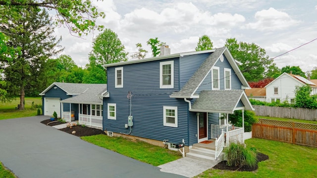 view of front of house with roof with shingles, covered porch, a chimney, and fence