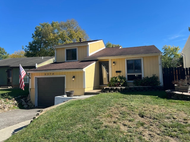 tri-level home featuring aphalt driveway, a garage, a front lawn, and fence