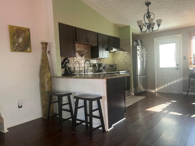 kitchen featuring backsplash, a kitchen bar, appliances with stainless steel finishes, dark wood-style floors, and a sink