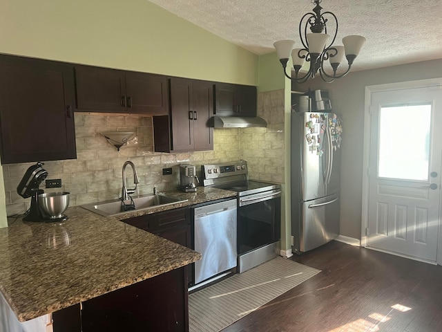 kitchen featuring dark wood-style flooring, a sink, decorative backsplash, stainless steel appliances, and a chandelier