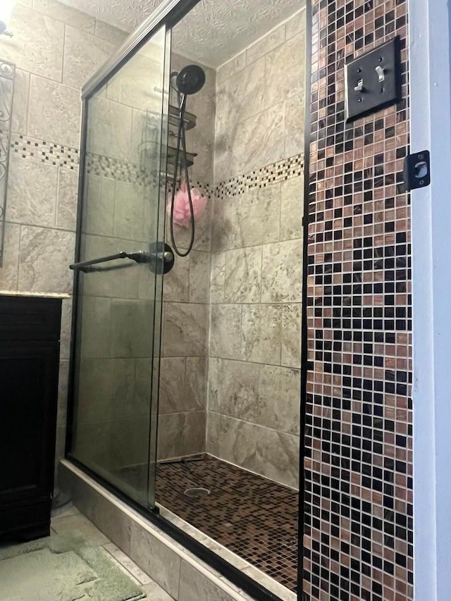 bathroom featuring a textured ceiling and a shower stall