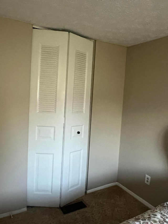 unfurnished bedroom featuring baseboards, a closet, a textured ceiling, and carpet