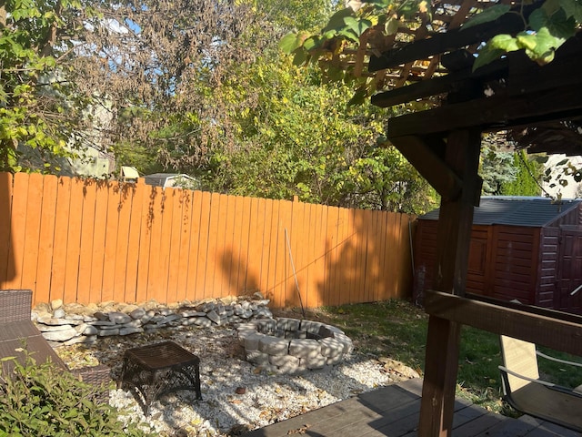 view of yard featuring an outbuilding, a fenced backyard, a storage shed, and an outdoor fire pit