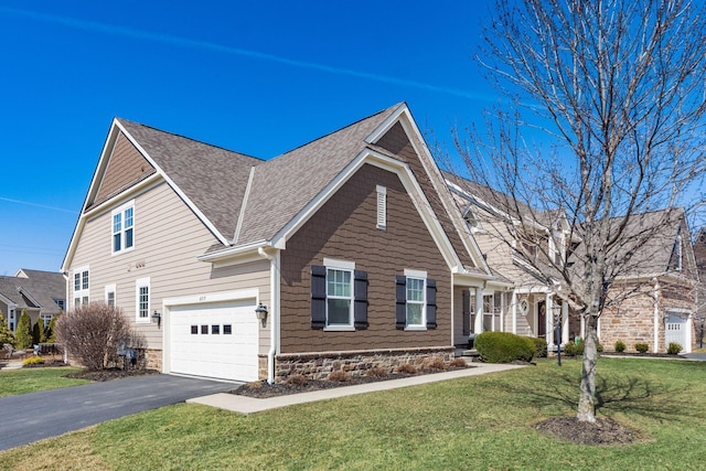 view of front of house with a front yard, an attached garage, driveway, and a shingled roof