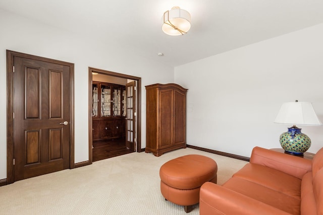 sitting room with baseboards and light carpet